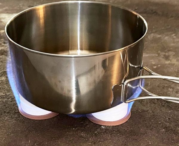 A steel pot set right on two Stones with blue flames under it