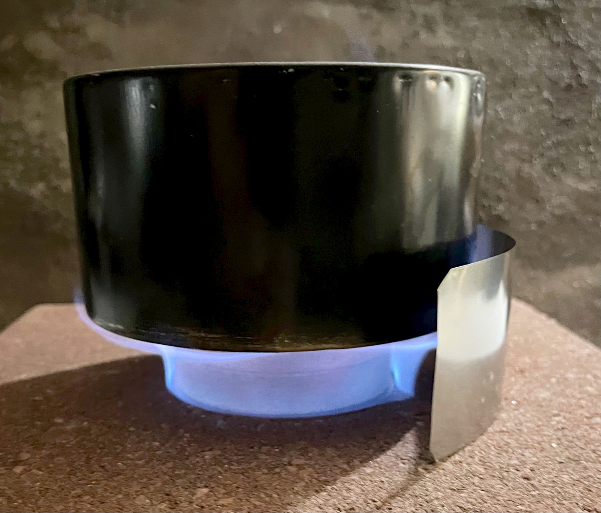 A quart pot inside a windscreen over a strong blue flame